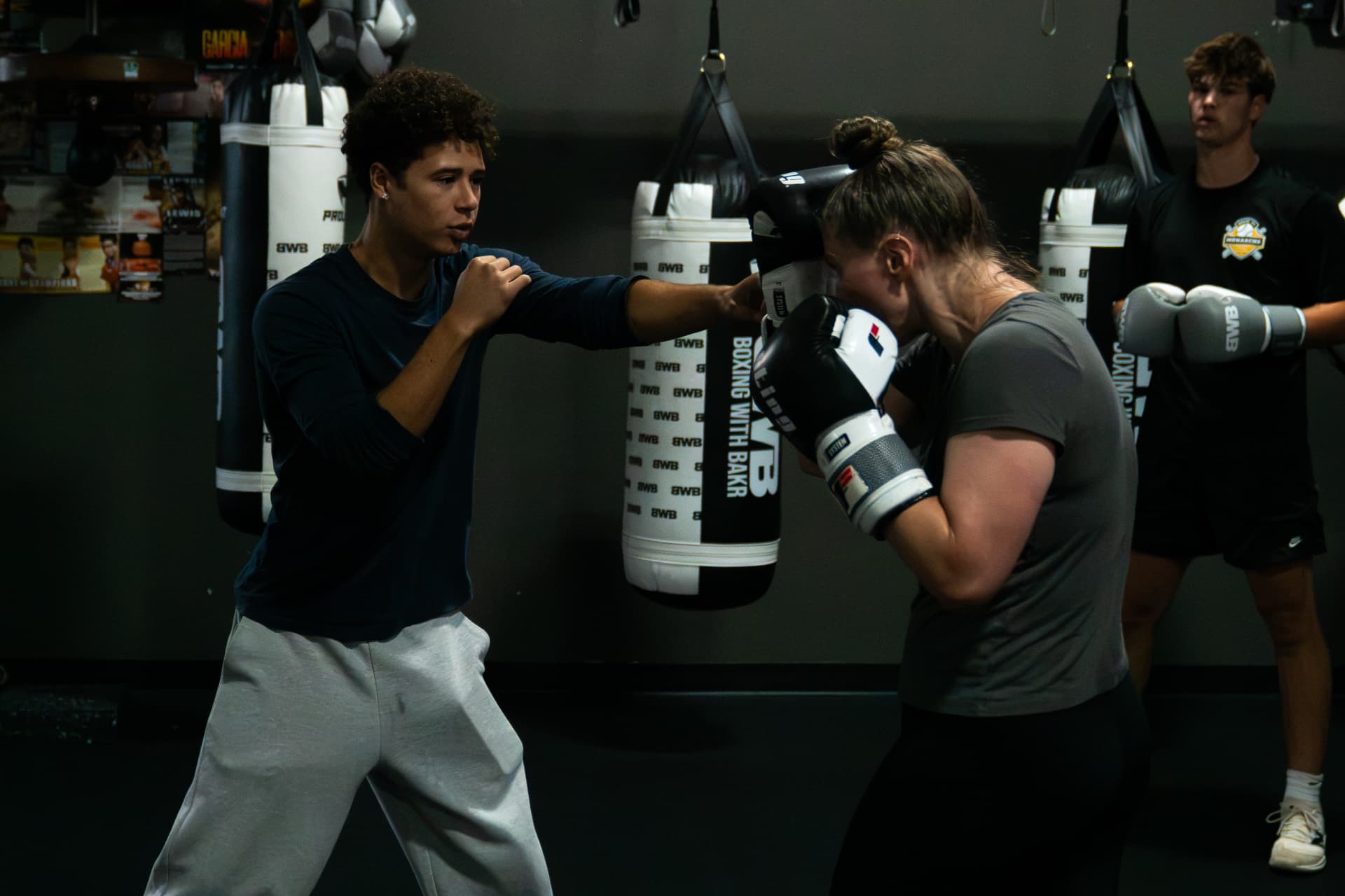 Devin coaching two boxers working the pads at Boxing With Bakr