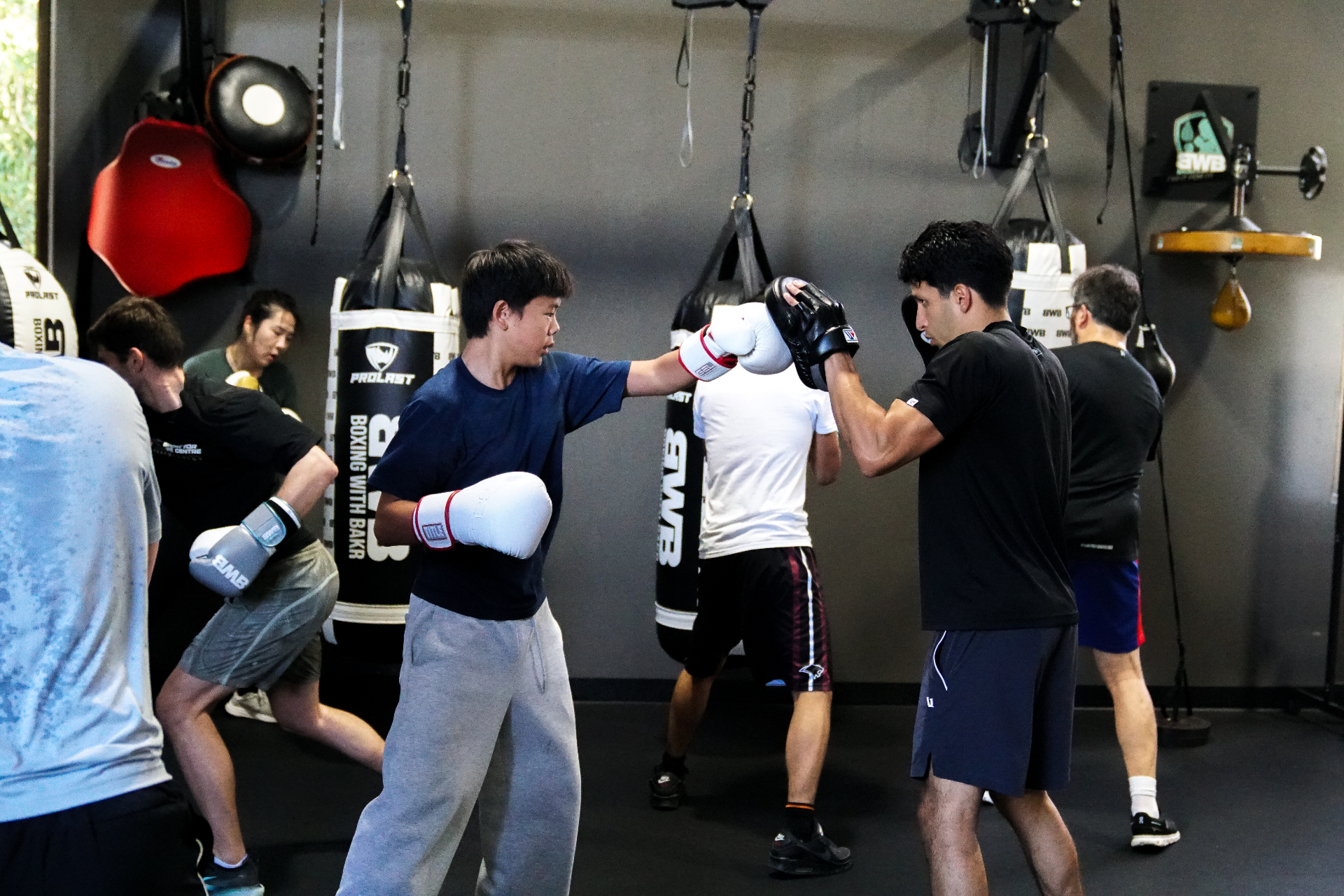 Youth Programming — Coach Bakr holding mitts for a youth athlete in a BWB youth session