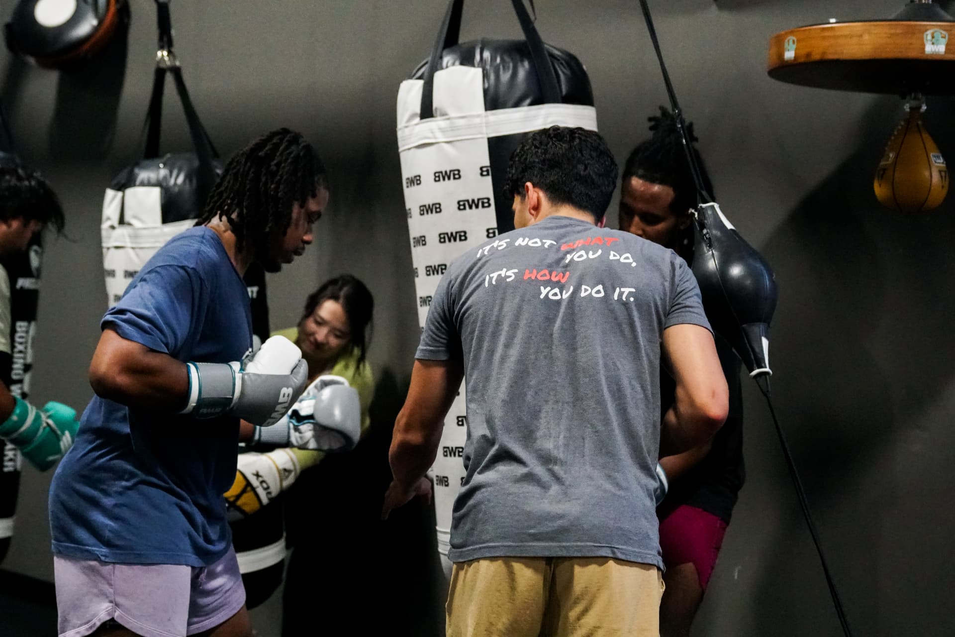 Boxers gloving up on the heavy bag wall at Boxing With Bakr