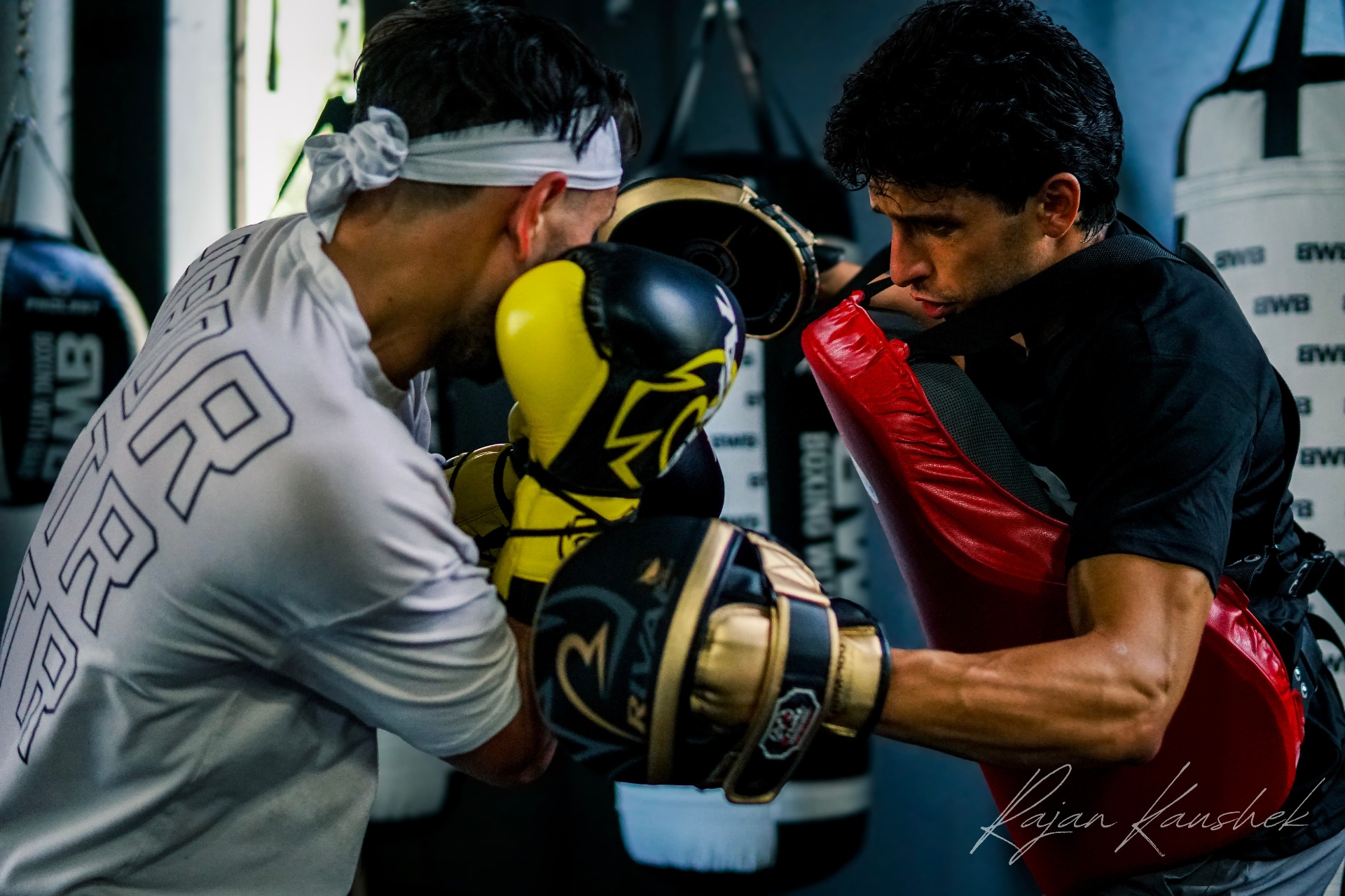 Coach Bakr holding mitts for pro fighter Charlie Sheehy — close-quarters combination work