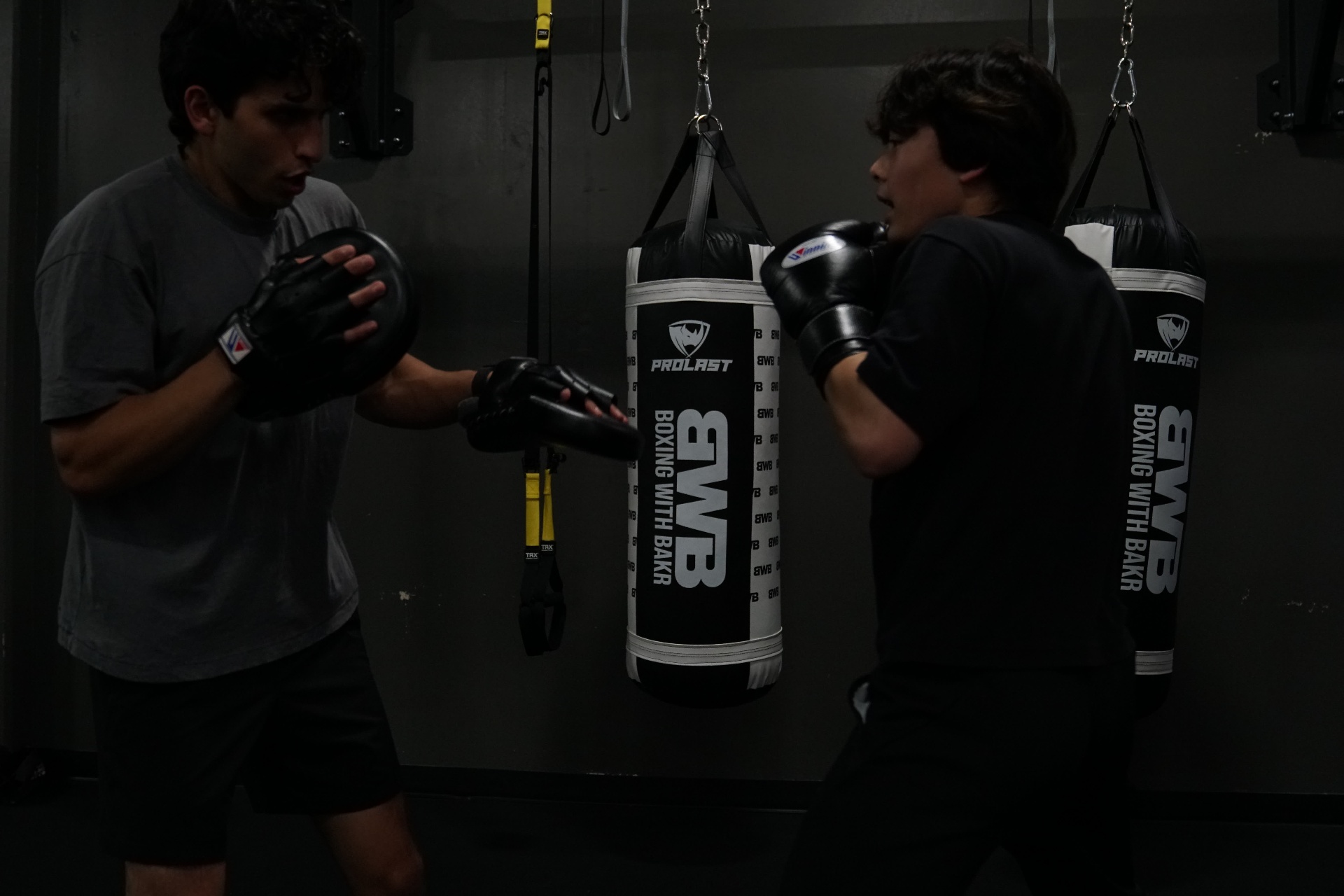 Coach holding mitts for a young fighter in the BWB bag room