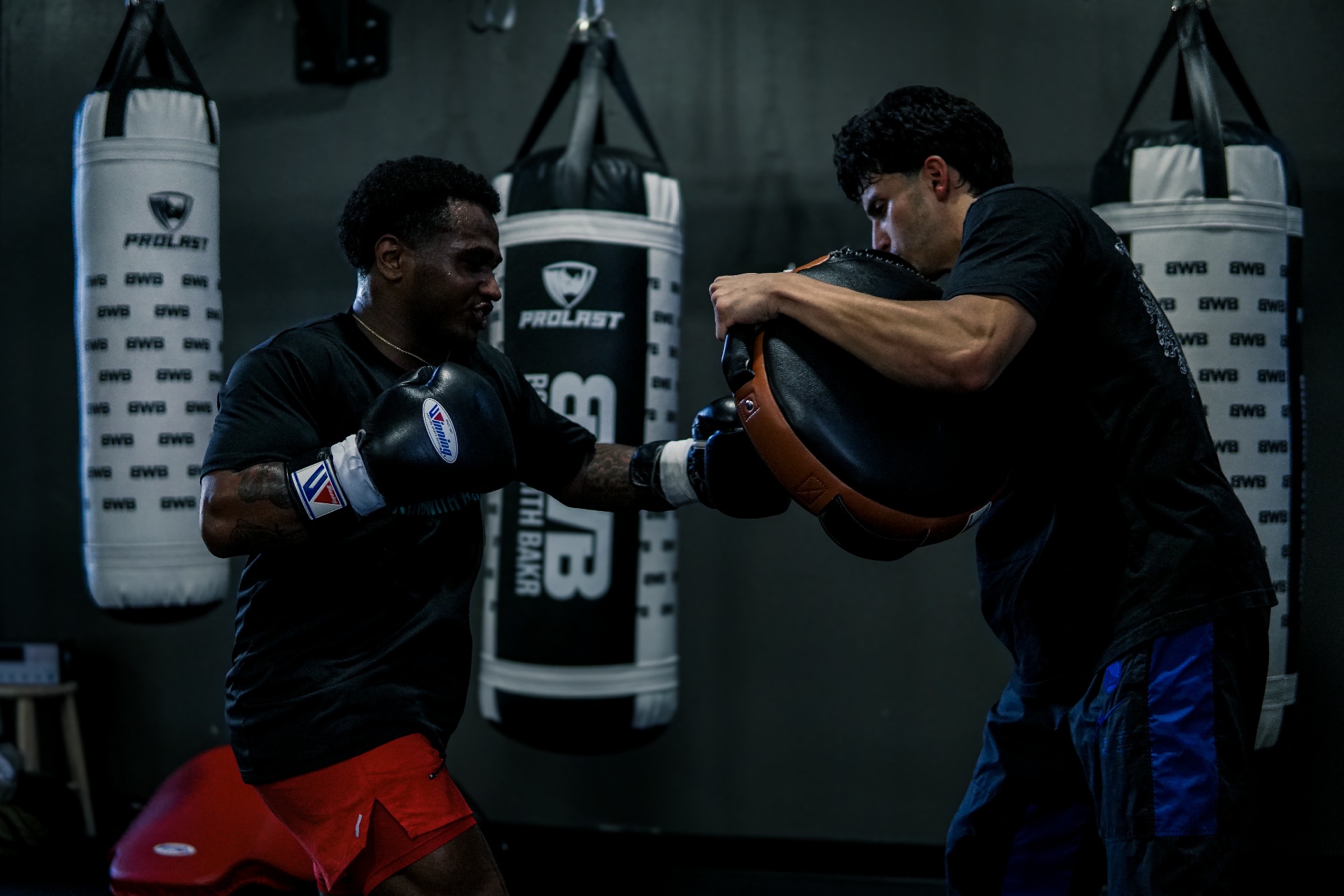 Steve throwing a cross on the mitts with Coach Bakr in the bag room