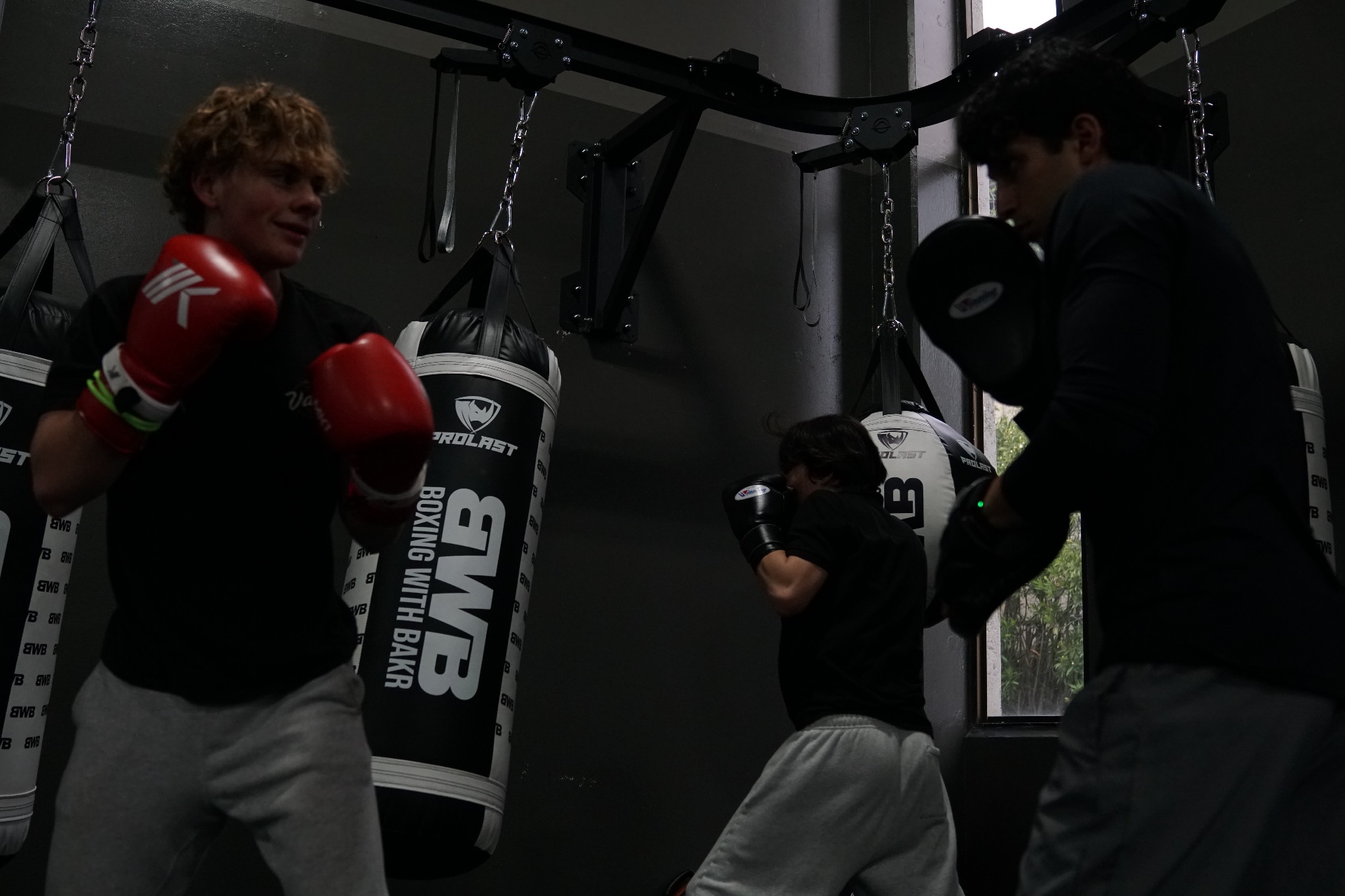 Youth Programming — Teen athletes working heavy bags and mitts together at Boxing With Bakr's youth program